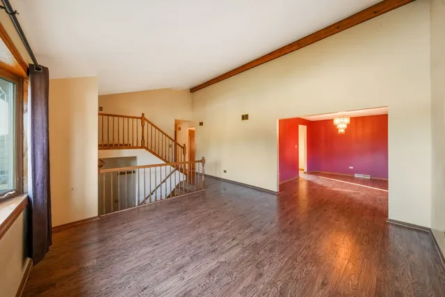 a view of an empty room with wooden floor and stairs