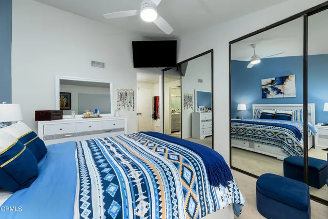 a bedroom with a bed a couch and a flat screen tv