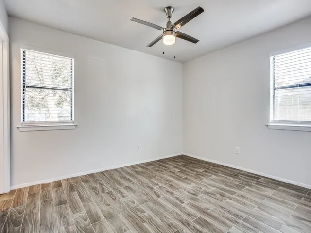 a view of empty room with wooden floor and fan