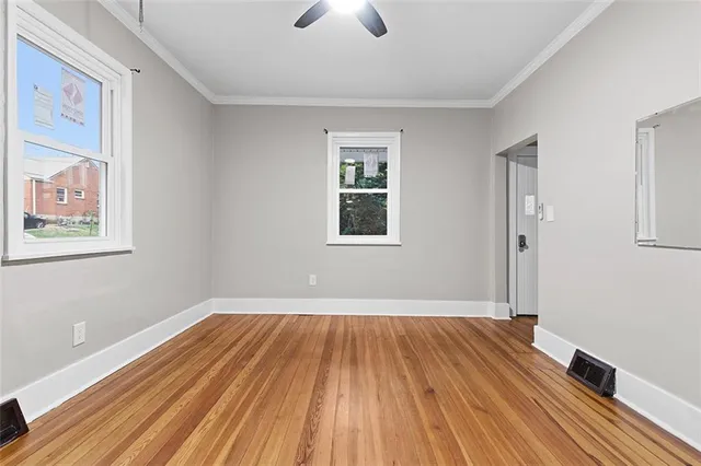 a view of a room with wooden floor a ceiling fan and windows