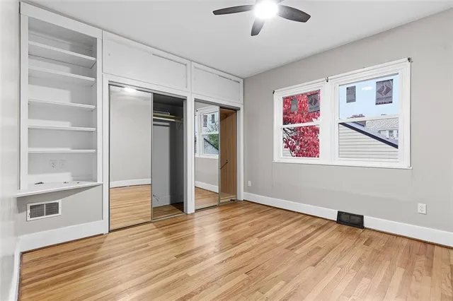 a view of an empty room with a window and wooden floor