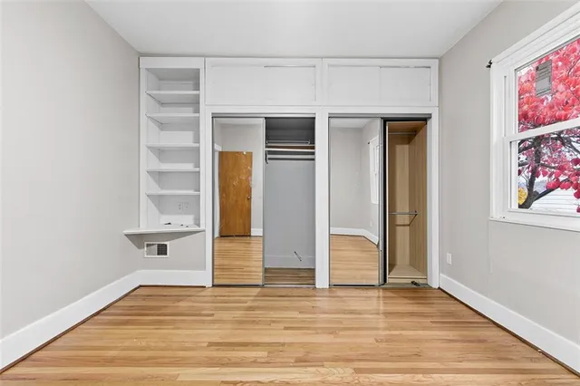a view of an empty room with wooden floor and closet