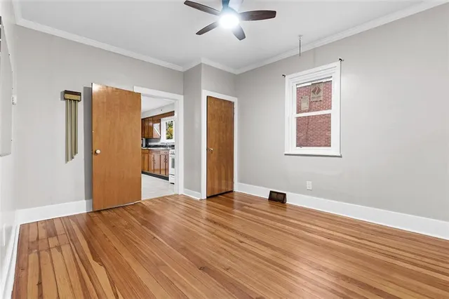 a view of an empty room with wooden floor and a window