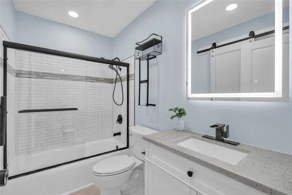 a bathroom with a granite countertop sink toilet and shower