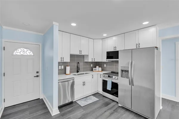 a kitchen with white cabinets and stainless steel appliances