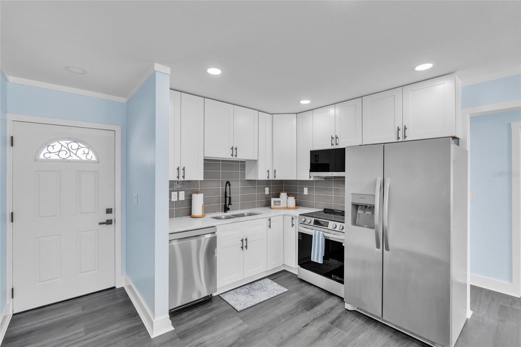 445 63rd Street Holmes Beach, FL 34217 - Photo 5 of 45 a kitchen with white cabinets and stainless steel appliances