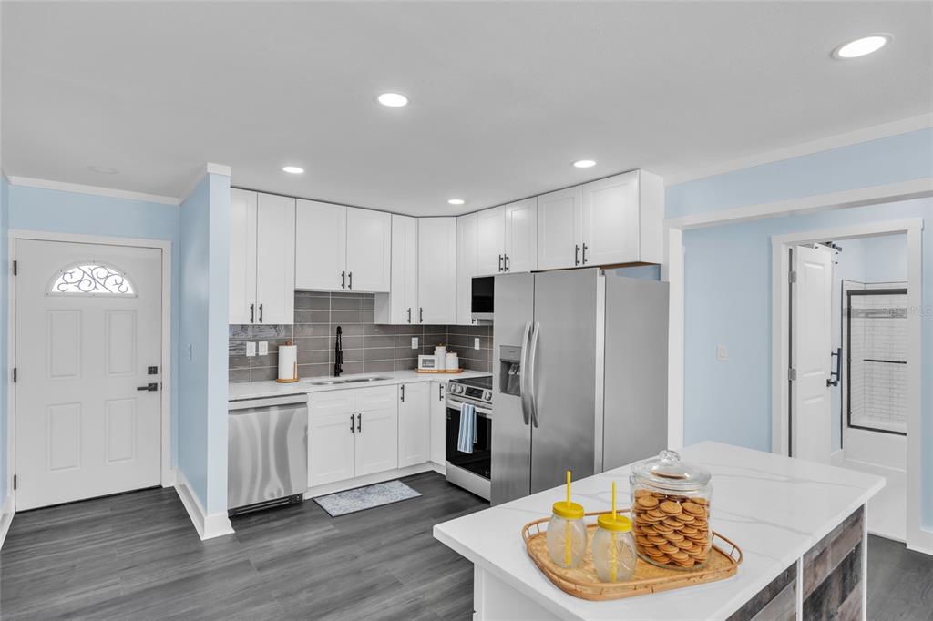 445 63rd Street Holmes Beach, FL 34217 - Photo 6 of 45 a kitchen with stainless steel appliances kitchen island granite countertop a refrigerator a sink a stove and white cabinets with wooden floor