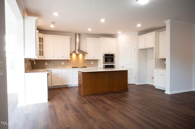 a large kitchen with stainless steel appliances granite countertop a white cabinets a stove a sink and a refrigerator