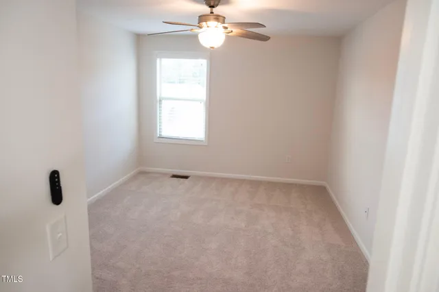 an empty room with a window and a fan