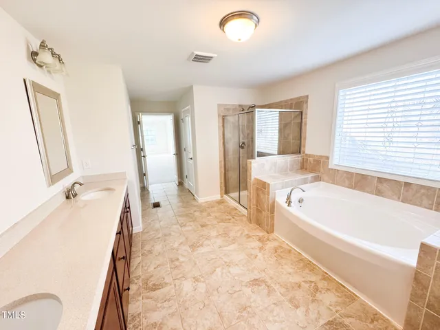 a spacious bathroom with a tub sink and a large mirror