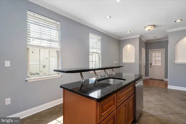 a kitchen island with granite countertop a sink and a window
