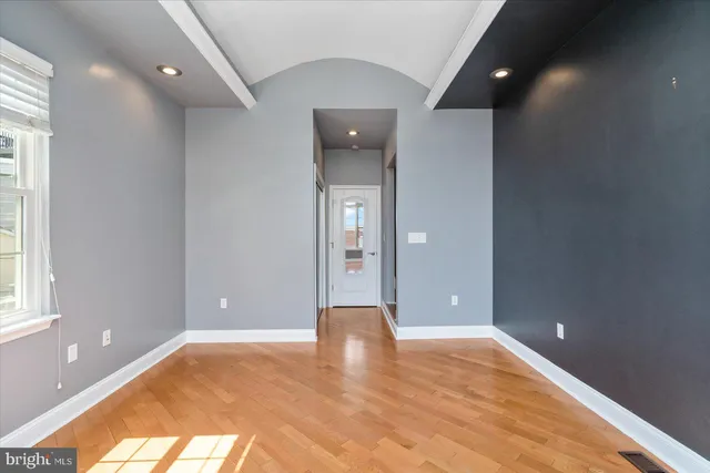 a view of an empty room with wooden floor and a window