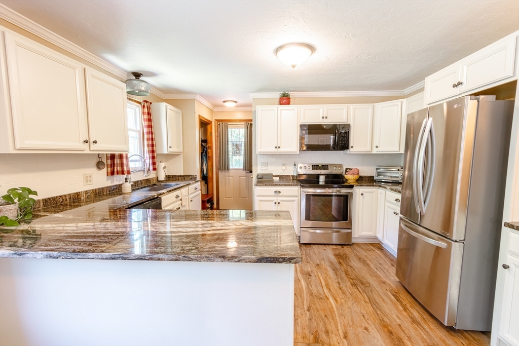 27 Comins Road North Oxford, MA 01537 - Photo 5 of 32 a kitchen with stainless steel appliances granite countertop a refrigerator a stove and a sink with wooden floor