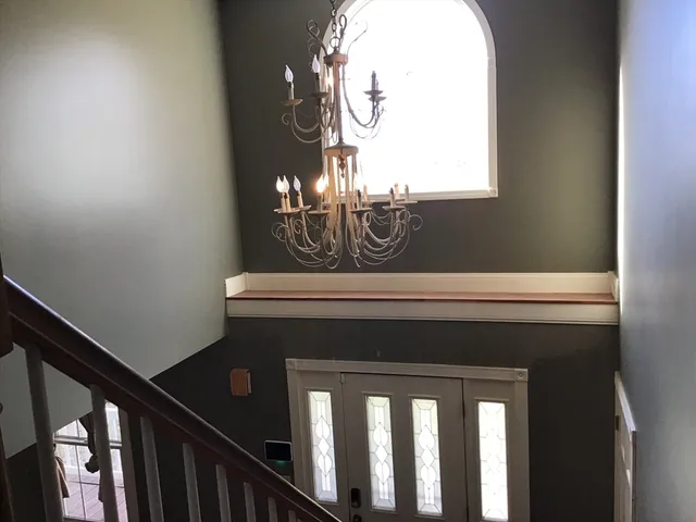 a view of staircase with railing and a chandelier