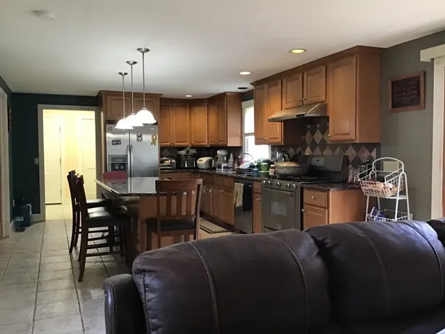 a kitchen with granite countertop a sink chairs and refrigerator
