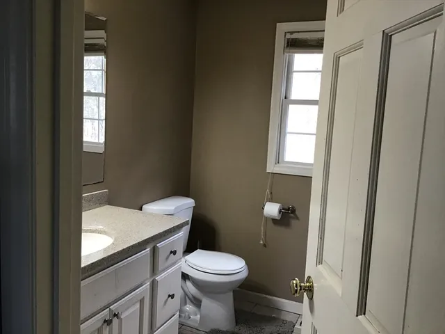 a bathroom with a granite countertop toilet a sink and a mirror