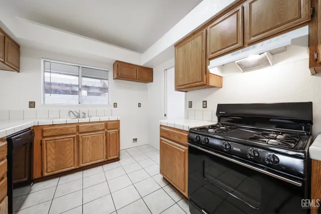 a kitchen with granite countertop a stove top oven cabinetry a sink and a window