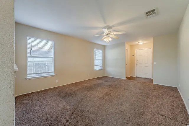 an empty room with windows and fan