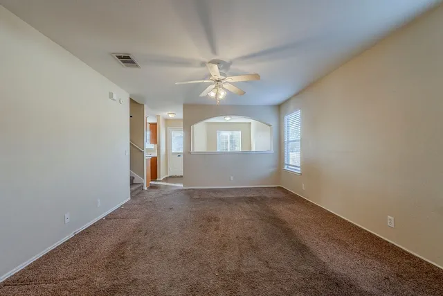 an empty room with a window and a ceiling fan