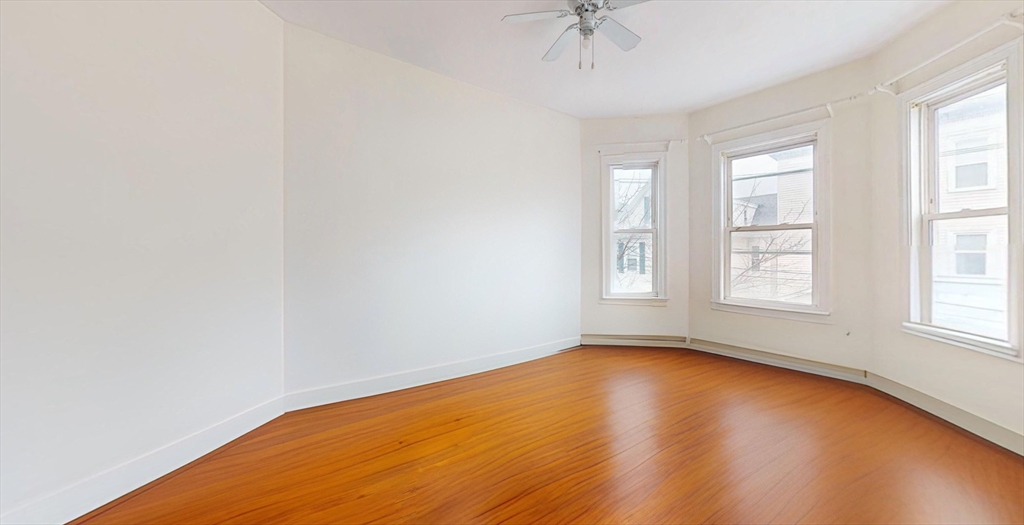 19 Newport Street, Unit 2 Boston, MA 02125 - Photo 7 of 13 an empty room with wooden floor chandelier fan and windows