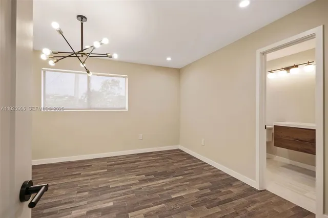 an empty room with wooden floor closet and windows