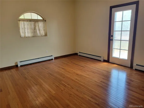 an empty room with wooden floor cabinet and windows