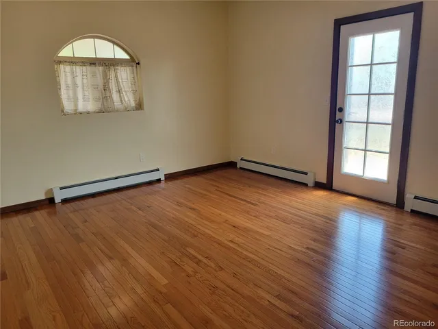 an empty room with wooden floor cabinet and windows