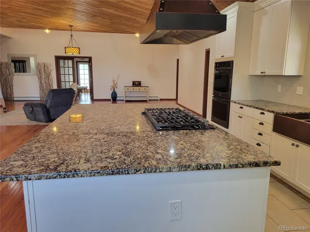 a kitchen with stainless steel appliances granite countertop a sink a stove and a wooden cabinets