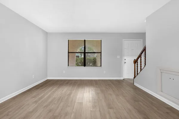 a view of an empty room with wooden floor and a window