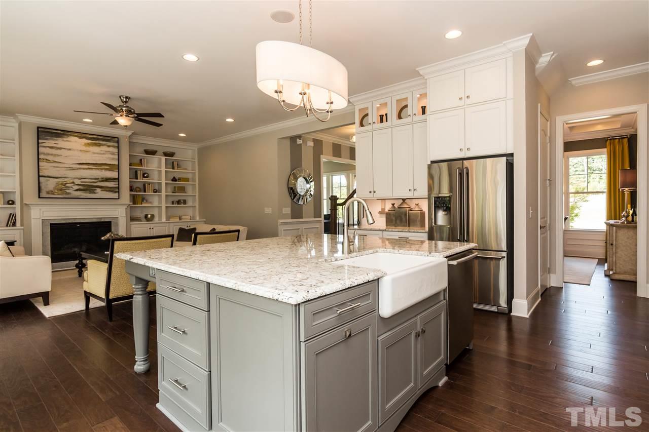 520 Belle Gate Place Cary, NC 27519 - Photo 12 of 25 a large kitchen with a center island wooden floor stainless steel appliances and living room view