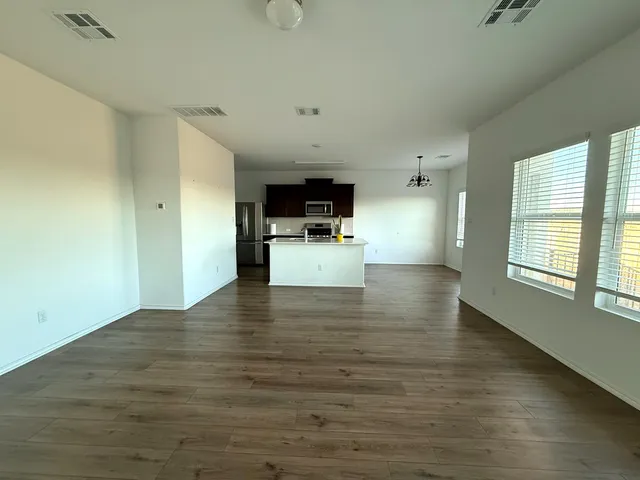 a view of empty room with kitchen and window