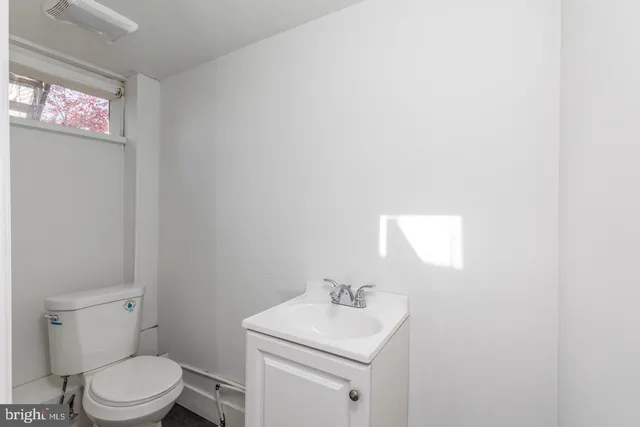 a bathroom with a toilet sink vanity and mirror