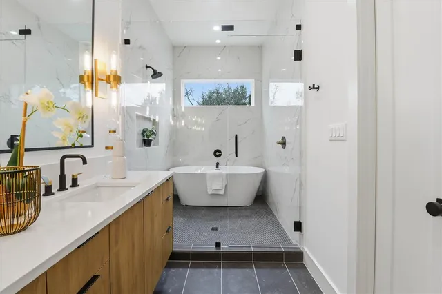 a bathroom with a tub sink double vanity and mirror