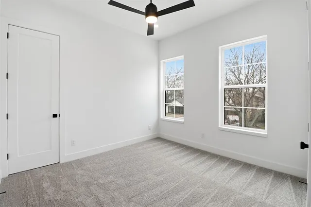 an empty room with windows and ceiling fan