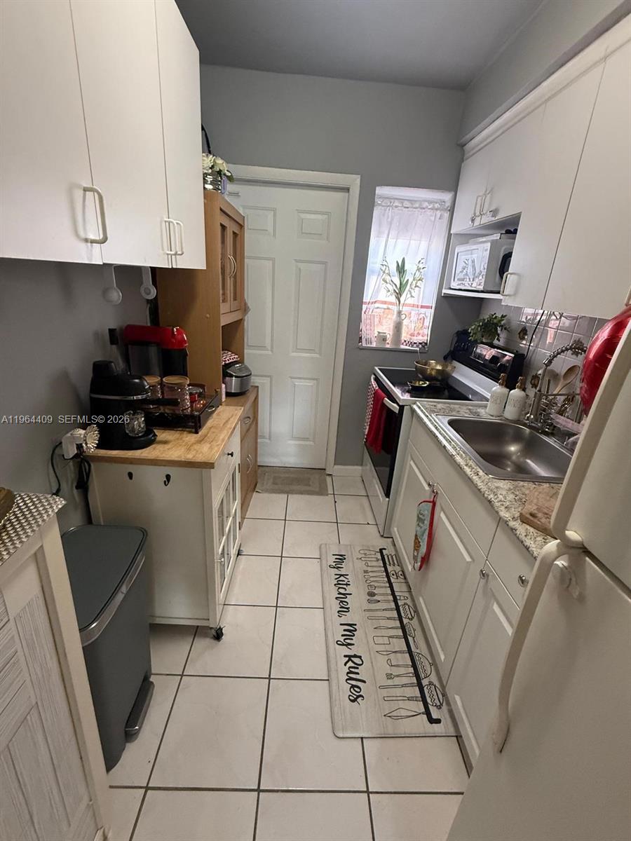 3411 Southwest 11th Street, Unit 3B Miami, FL 33135 - Photo 5 of 14 a kitchen with granite countertop a stove top oven a sink a counter space and cabinets