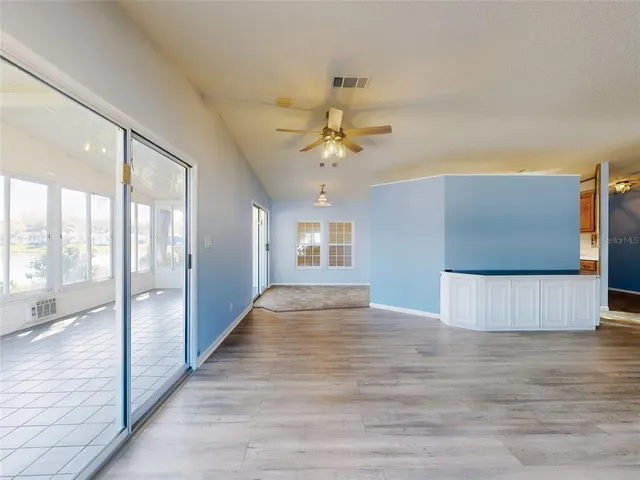 a view of an empty room with window and a kitchen