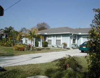 9345 Southeast Delafield Street Hobe Sound, FL 33455 - Photo 1 of 5 a front view of house with yard and green space