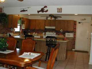 9345 Southeast Delafield Street Hobe Sound, FL 33455 - Photo 3 of 5 a kitchen with a refrigerator a stove a sink and a dining table with wooden floor