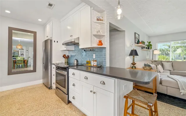 a kitchen with stainless steel appliances granite countertop a refrigerator and a stove top oven