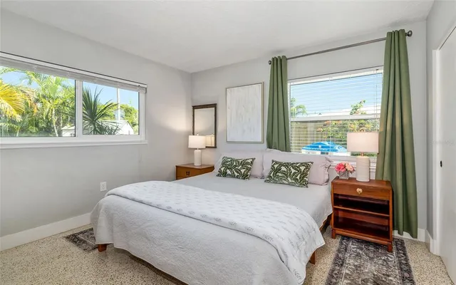 a bedroom with a bed and large windows