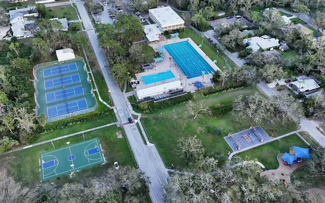 an aerial view of residential house with outdoor space and trees all around