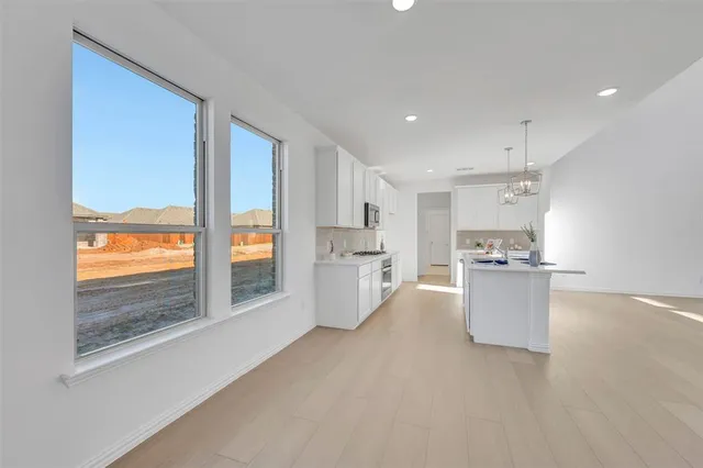 a room with a large window and a kitchen view
