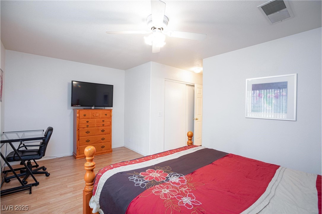 3673 Ian Thomas Street, Unit 102 Las Vegas, NV 89129 - Photo 8 of 15 Bedroom with light wood-style floors, a closet, a desk, and a ceiling fan