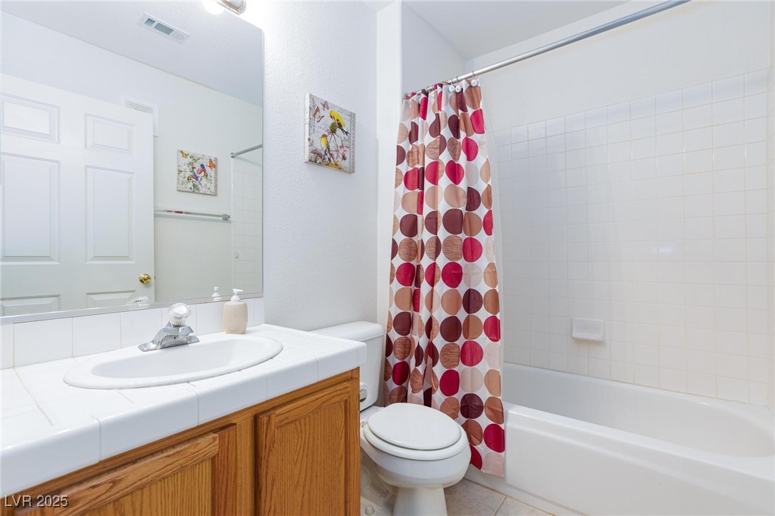 3673 Ian Thomas Street, Unit 102 Las Vegas, NV 89129 - Photo 9 of 15 Bathroom featuring vanity, shower / bath combination with curtain, and light tile patterned floors