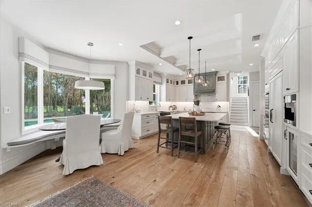 a dining room with kitchen island stainless steel appliances furniture a large window and a chandelier
