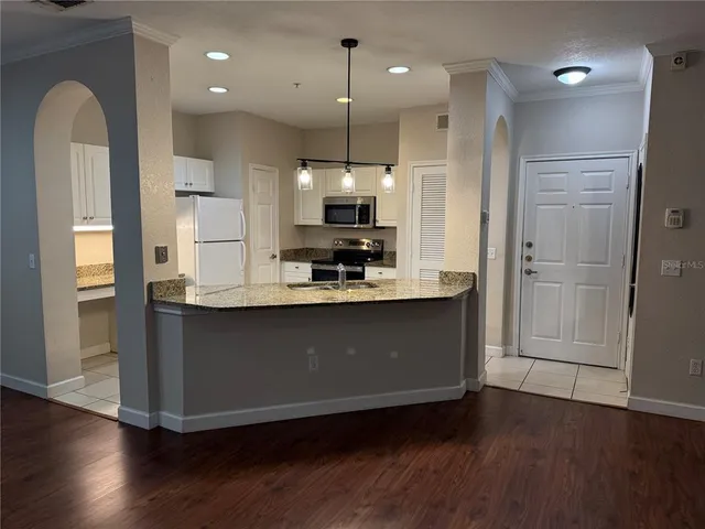 a kitchen with kitchen island a refrigerator a sink and wooden floor