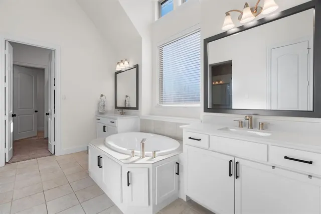 a bathroom with a bathtub a mirror a sink and vanity