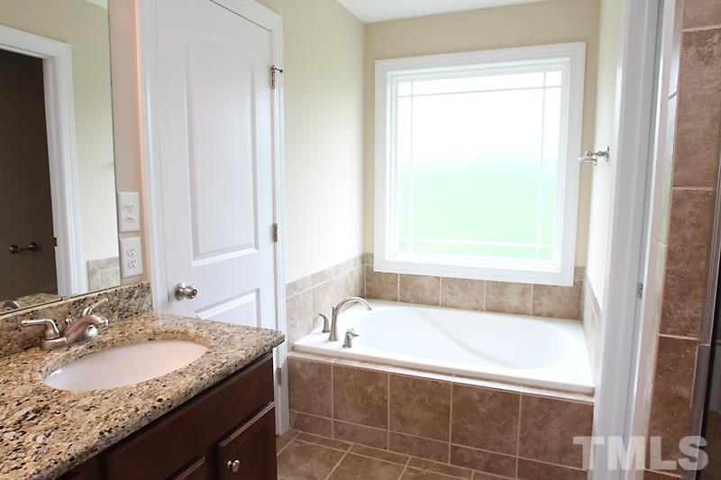 7332 Denlee Road Raleigh, NC 27603 - Photo 16 of 24 a bathroom with a granite countertop tub sink and mirror