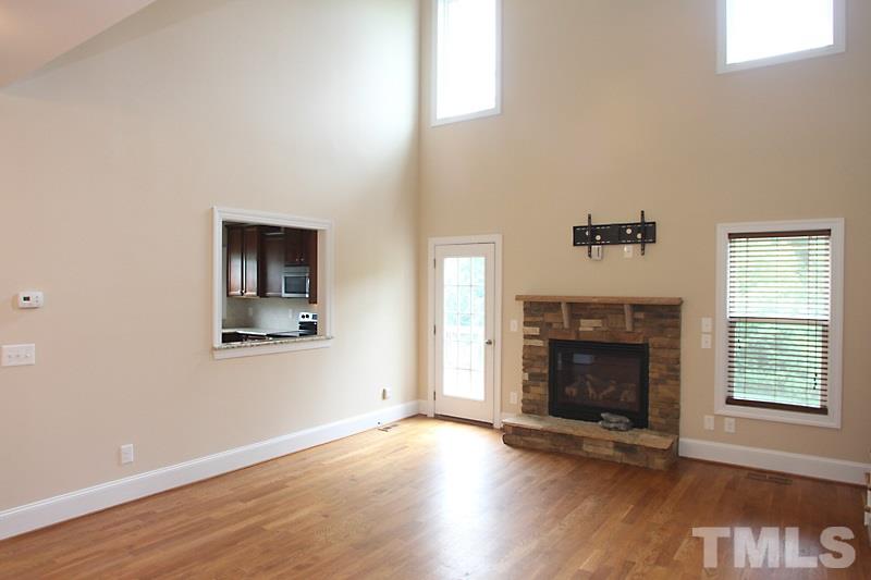 7332 Denlee Road Raleigh, NC 27603 - Photo 4 of 24 an empty room with wooden floor fireplace and windows