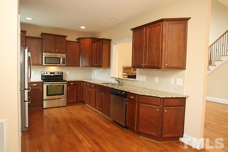 7332 Denlee Road Raleigh, NC 27603 - Photo 9 of 24 a kitchen with granite countertop wooden floors stainless steel appliances and a window